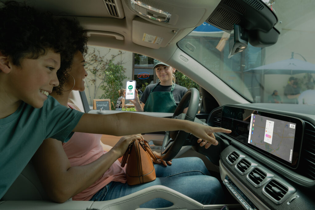 Shows a driver confirming a curbside pick up payment through their vehicles infotainment system. The curbside pick up employee also shows that it has been paid on their end